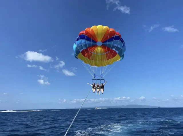 石垣島の空を飛ぶアクティビティ、パラセーリングで空中散歩を楽しむ観光客。
